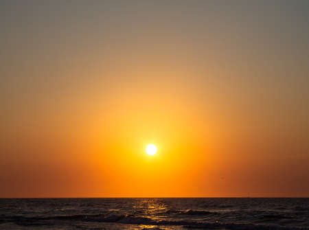 Romantic sunset by the sea. The setting sun over the waves.の写真素材