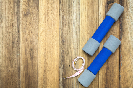 Fitness and sport equipment : Measuring tape,dumbells with wooden background on top viewの写真素材