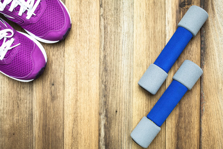 Fitness and sport equipment :sneakers and dumbbells with wooden background on top viewの写真素材