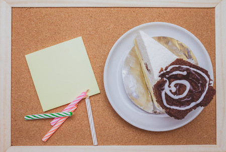 Cake,colorful candles and post it on cork board backgroundの写真素材
