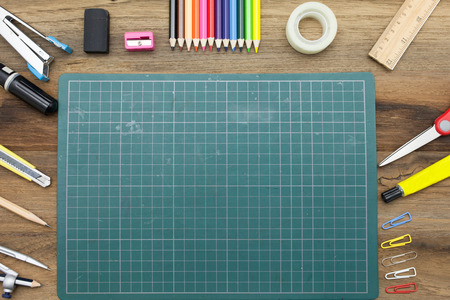 Business concept:stapler,glue,scissor,cutter,tape,pen,pencil,clip,ruler,rubber, cutting mat,divider,sharpener,wooden block calendar and color pencil on wooden background.Top viewの写真素材