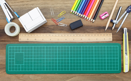 Business concept:stapler,glue,scissor,cutter,tape,pen,pencil,clip,ruler,rubber, cutting mat,divider,sharpener,wooden block calendar and color pencil on wooden background.Top viewの写真素材