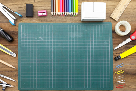 Business concept:stapler,glue,scissor,cutter,tape,pen,pencil,clip,ruler,rubber, cutting mat,divider,sharpener,wooden block calendar and color pencil on wooden background.Top viewの写真素材