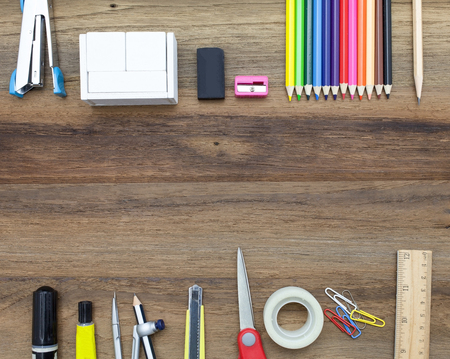 Stapler,glue,scissor,cutter,tape,pen,pencil,clip,ruler,rubber, cutting mat,divider,sharpener,ruler,wooden block calendar and color pencil on wooden backgroundの写真素材