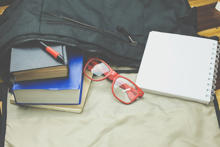 Top view of casual life style bag ; Old book,notebook,red glasses and casual shoes from inside bag.の写真素材