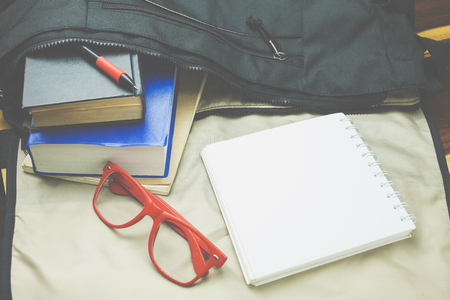 Top view of casual life style bag ; Old book,notebook,red glasses and casual shoes from inside bag.の写真素材
