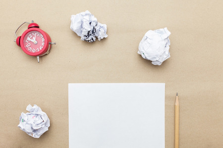 Business concept:red clock,white blank paper,crumpled paper and pencil on brown paper backgroundの写真素材