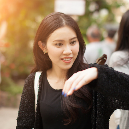 Woman enjoying Butterfly perched on her hand at the parkの写真素材