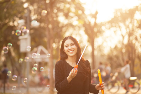 Pretty Thai girl blowing a bubbles at the parkの写真素材