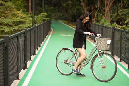 Pretty Thai girl rides bicycle at the parkの写真素材