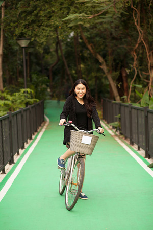 Pretty Thai girl rides bicycle at the parkの写真素材