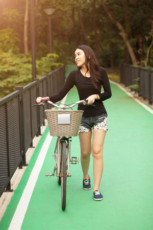 Pretty Thai girl rides bicycle at the parkの写真素材
