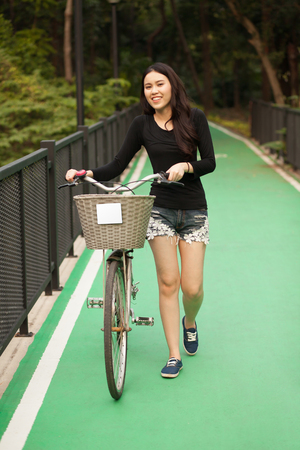 Pretty Thai girl rides bicycle at the parkの写真素材
