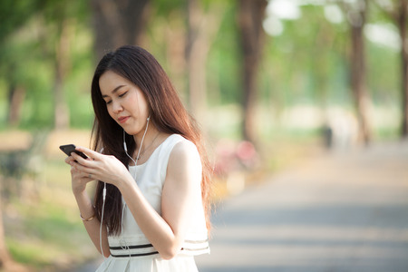 woman using earphone and smartphone at parkの写真素材