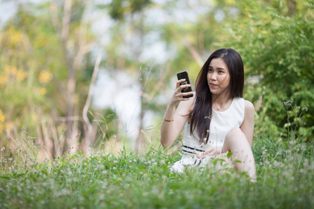 Thai pretty woman using mobile at the parkの写真素材