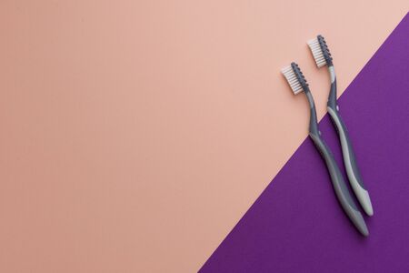 Two different grey  toothbrushes on a pink background. All you need for teeth.