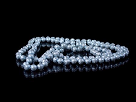 string of blue pearls isolated on black with reflectionの写真素材