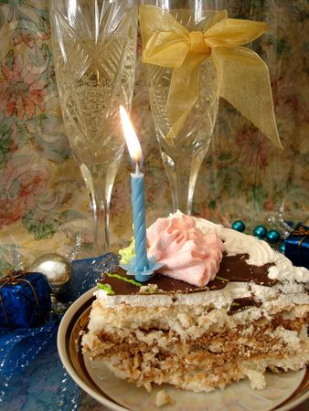 celebratory table (piece of birthday cake and blue candle, two glasses with champagne, gift boxes)の写真素材