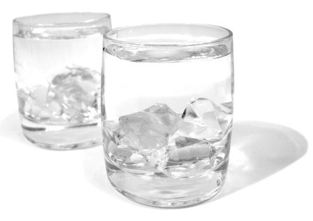 Glass with water and ice over whiteの写真素材