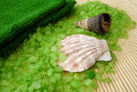 green towel, shells and salt on a straw mat の写真素材