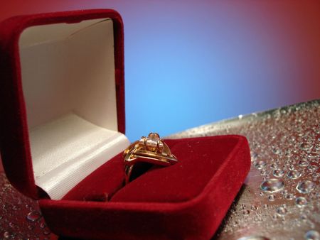 beautiful ring in box on blue and silver background with drop of water の写真素材
