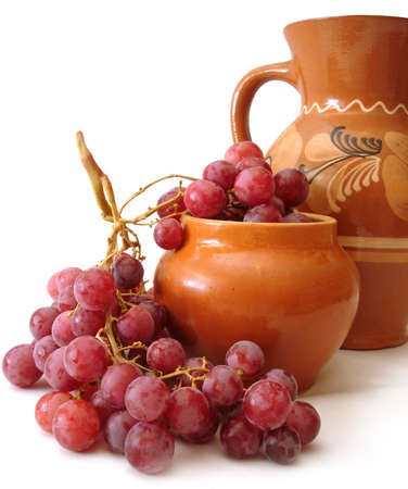 jug and red grapes over white background の写真素材