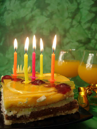 celebratory table (cake and candles, two glasses) on green 
