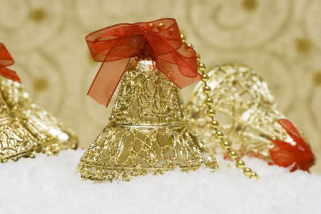 golden Christmas bells with red ribbon on snow の写真素材