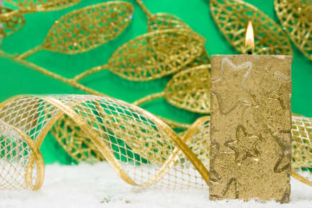 golden candle and ribbon on snow の写真素材