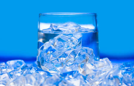 Glass with water and ice over blue の写真素材