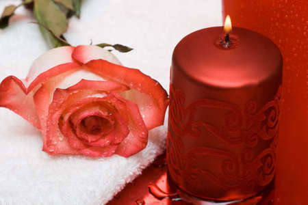 Candle with rose and towel on red background の写真素材