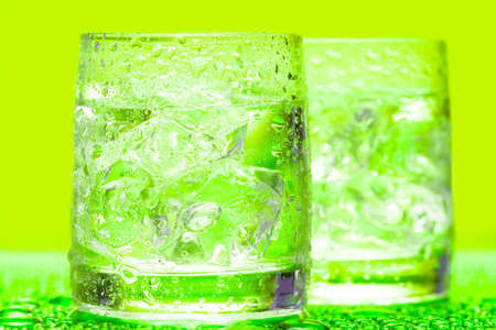 Glass with water and ice over greenの写真素材