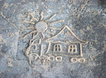 child's picture on stone is a cottage and sun の写真素材