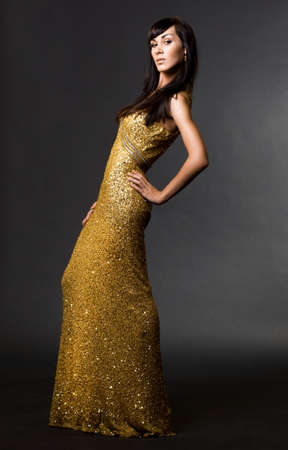 beautiful fashionable woman in golden dressの写真素材