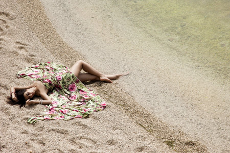 girl lying on the sand by the seaの写真素材