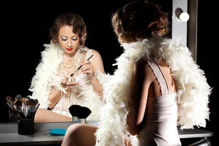 fashionable woman with make-up brush near the mirror