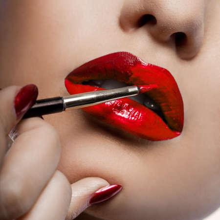 Girl paints her lips with lipstickの写真素材