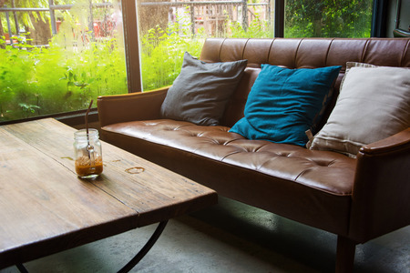 Leather sofa with a glass of water on a wooden table in a coffee shop.