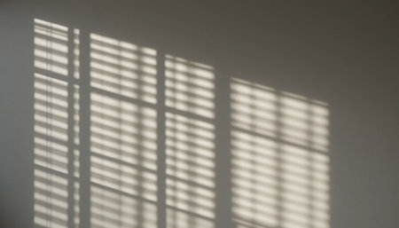 Soft light filters through window blinds, casting patterned shadows on the wall and creating a tranquil atmosphere.の素材