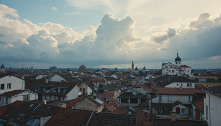 Rooftops of houses create a patchwork against a backdrop of dramatic clouds at sunset in a charming European town.の素材