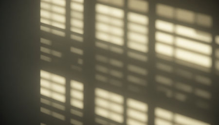 Soft light creates patterns on the wall as sunlight filters through wooden blinds in a quiet room.の素材