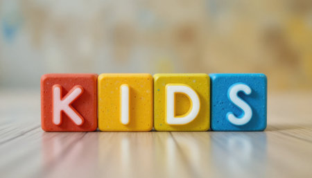Colorful building blocks arranged to form the word kids resting on a warm wooden surface, creating a playful vibe.の素材