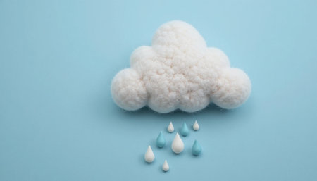 A fluffy white cloud is seen above colorful raindrops on a smooth blue surface, highlighting a whimsical weather scene.の素材