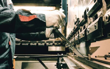 Worker bends metal on the machine. The old machine. A worker works in a factory.の写真素材
