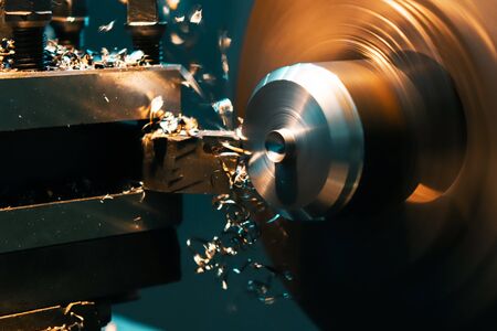 A turner grinds a part from an iron rod on a lathe. Metalworking parts on a lathe