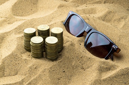 glasses and coins in the sandの写真素材