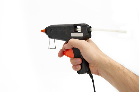 Hand holding glue gun isolated on the white backgroundの写真素材