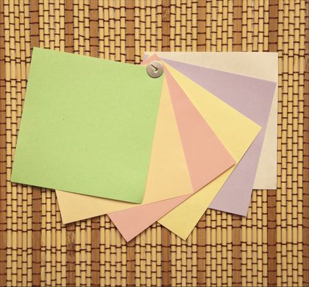 Colourful Notes fastened by the metal button on straw rug