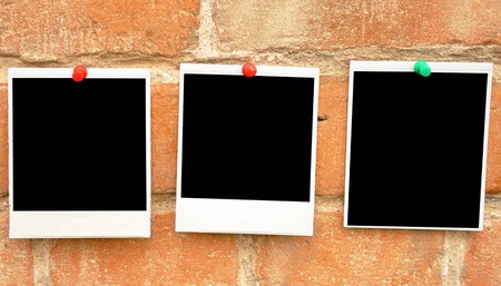 old photo pressed the red pushpin against a grungy brick wallの写真素材