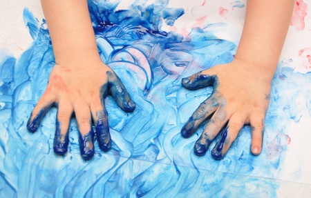child hands painted in blue paint ready for hand printsの写真素材